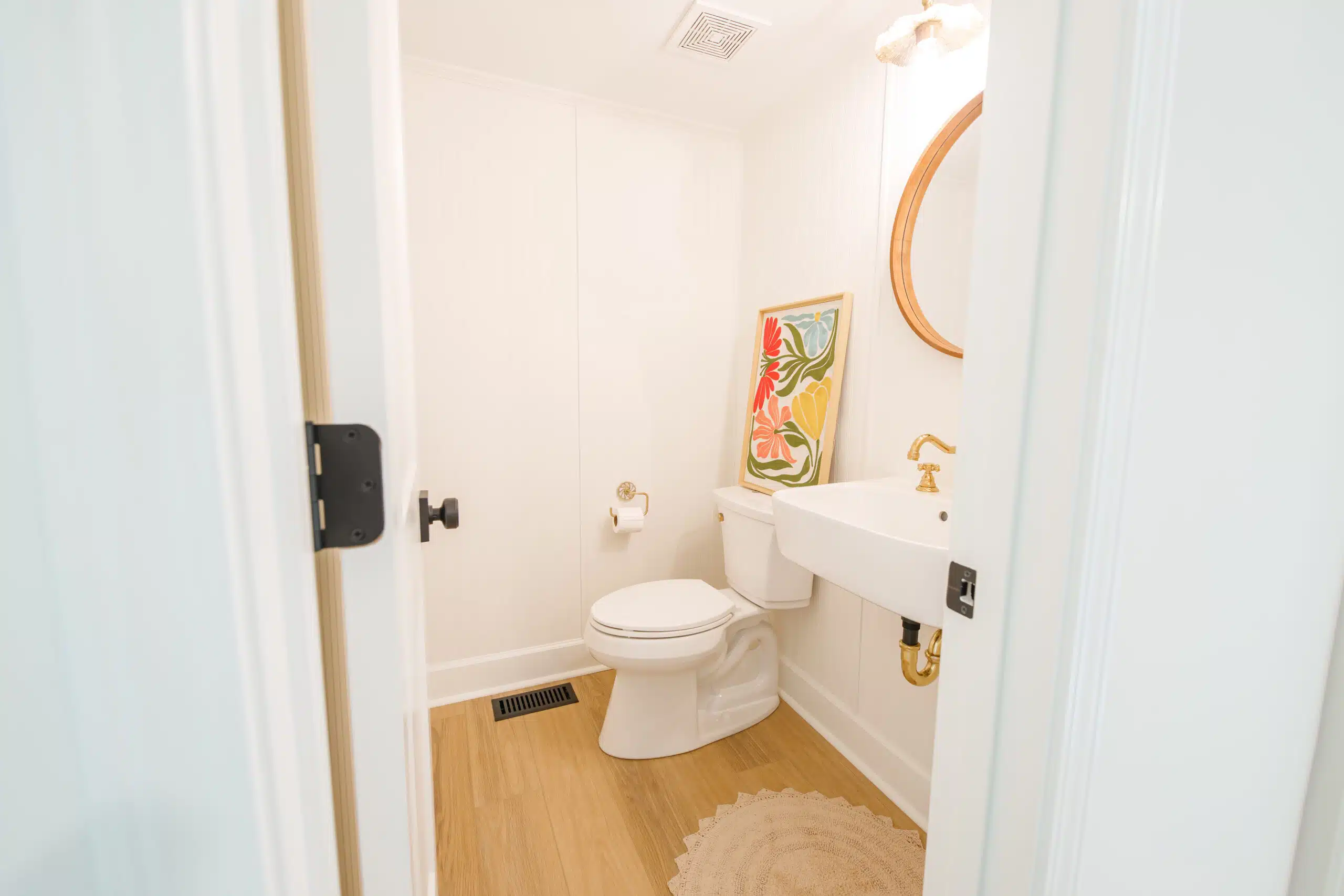 Small bathroom remodel with white vanity gold fixtures and round mirror by AG Construction Management