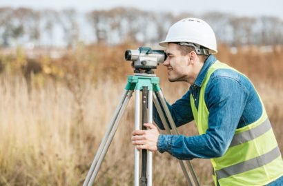 Side view of surveyor looking through digital level in field